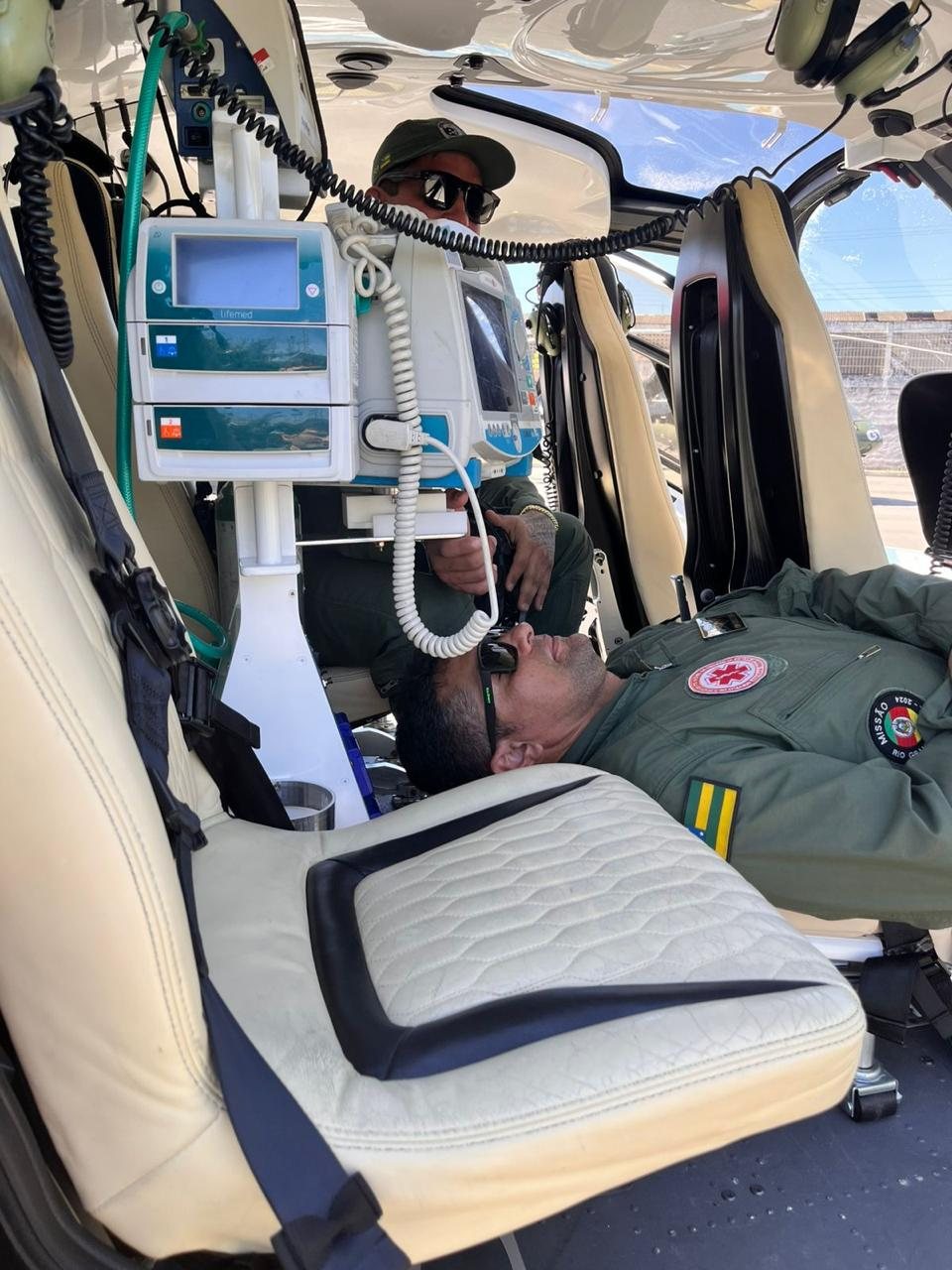 Tripulante ao lado do paciente com respirador montado no sistema aeromédico